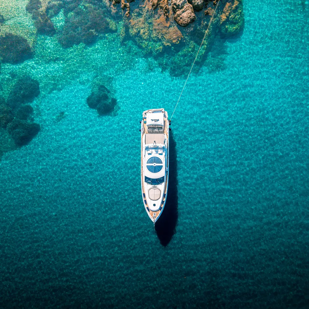 Vue aérienne au drone d'un yacht ancré dans une crique aux eaux turquoise, Corfou